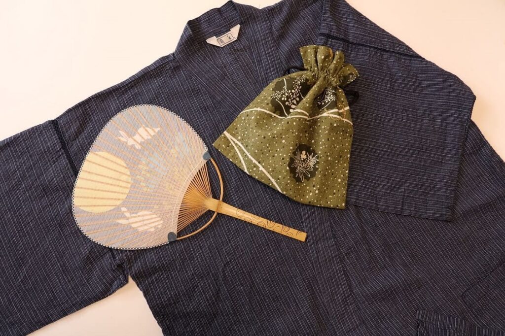 Men's traditional Japanese jinbei made from cotton and linen seersucker fabric, styled with a Japanese fan and drawstring pouch